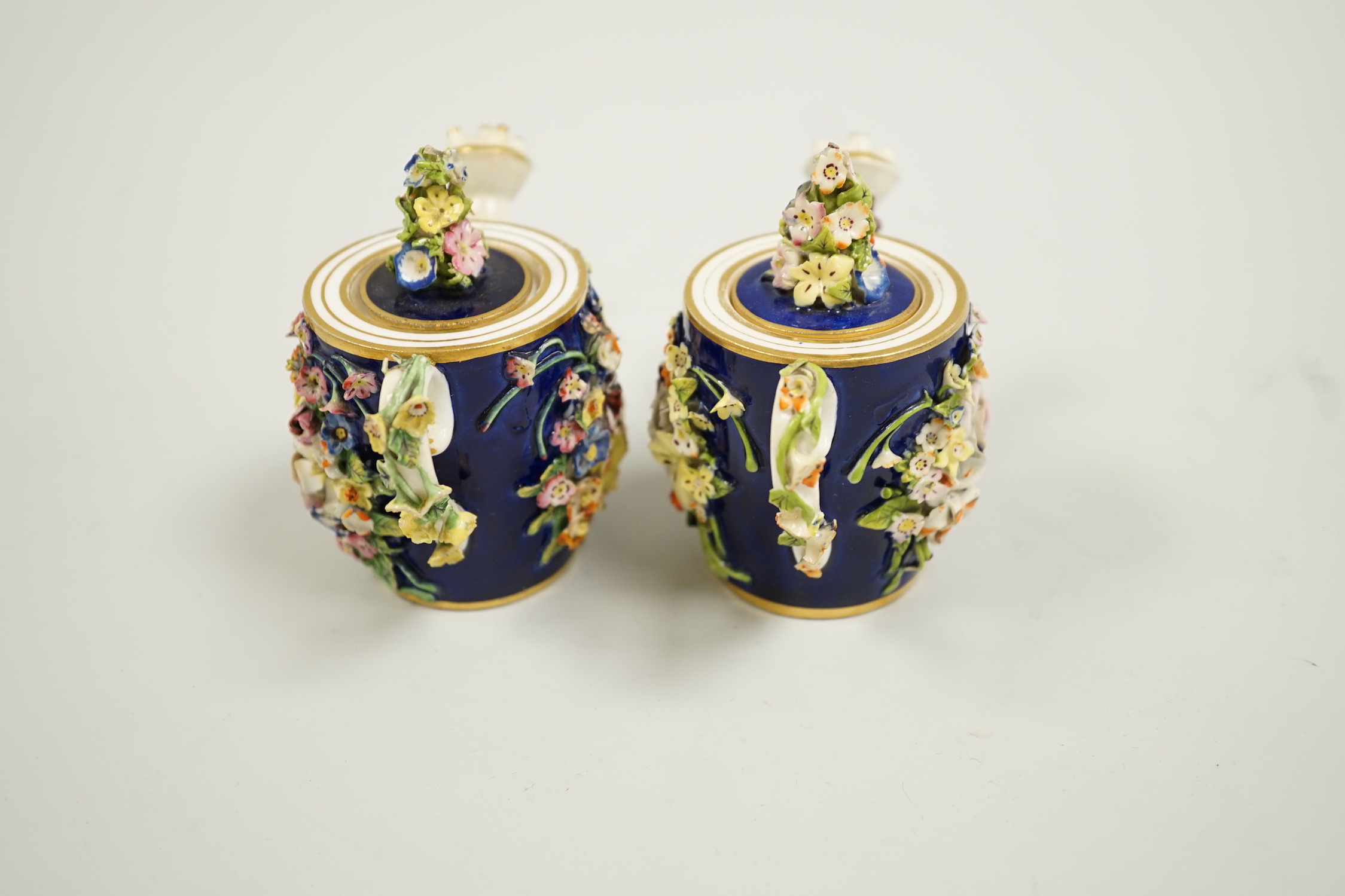 Toy porcelain. Two Bloor Derby flower encrusted rosewater sprinklers, each modelled as a watering can, c.1825, red printed marks, 9cm high
